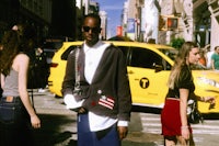 a woman walking down the street with a yellow taxi