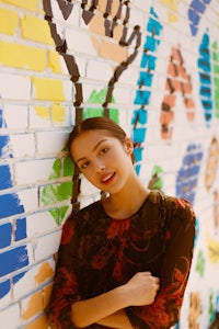 a young woman leaning against a colorful wall