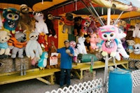 a man standing in front of a tent full of stuffed animals