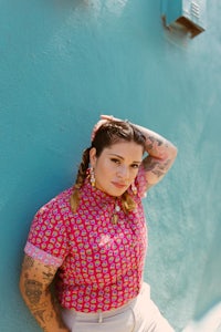 a woman with tattoos leaning against a blue wall