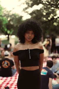 a woman in a black top and skirt standing on a picnic blanket