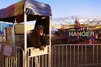 a man standing behind a fence at a carnival