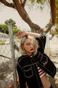 a woman leaning against a chain link fence