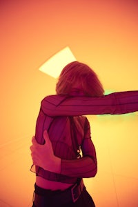 a woman is posing in an orange room