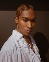 a young man in a white shirt and ear studs