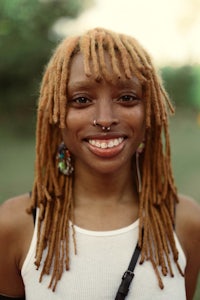 a woman with dreadlocks and piercings smiling