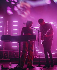 two people standing on stage in front of a purple light