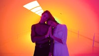 a man and a woman standing in front of a colorful tunnel