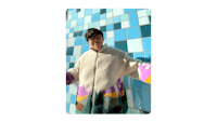 a woman in a colorful coat standing in front of a tiled wall
