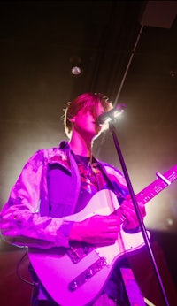 a young man playing a guitar in front of a microphone