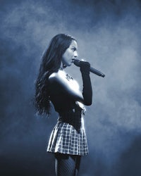 a woman in a plaid skirt singing into a microphone